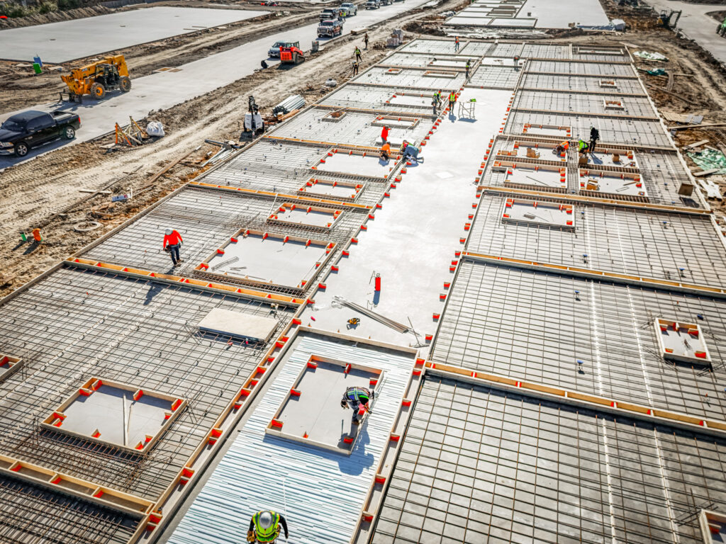 Aerial view of an active commercial construction job site with building foundations underway on a design-build project in Dallas-Fort Worth